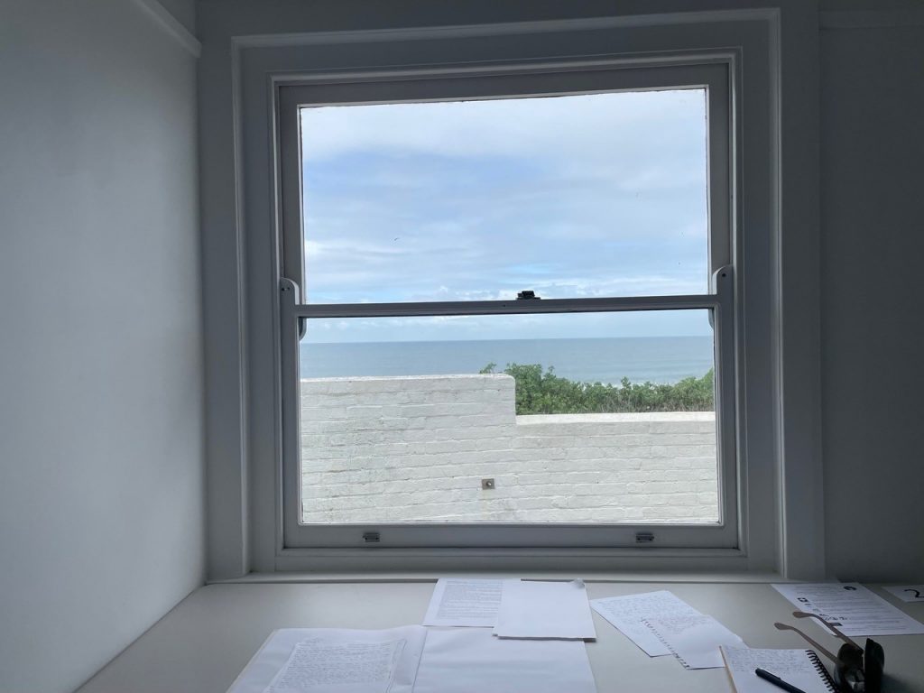 Studio space, papers on desk, ocean in background